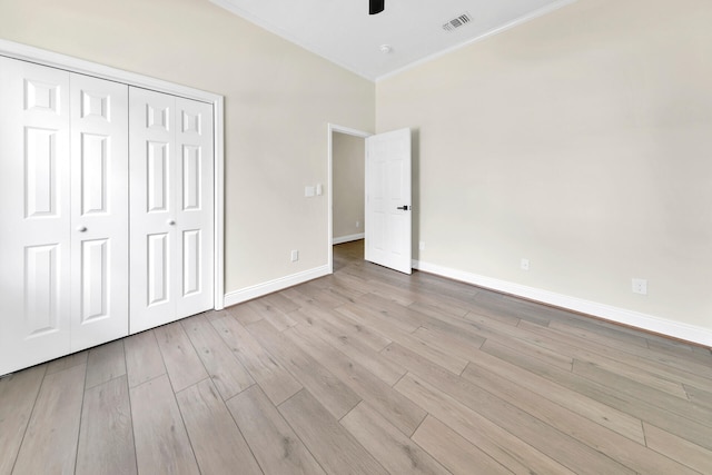 unfurnished bedroom featuring a closet, light hardwood / wood-style floors, crown molding, and ceiling fan