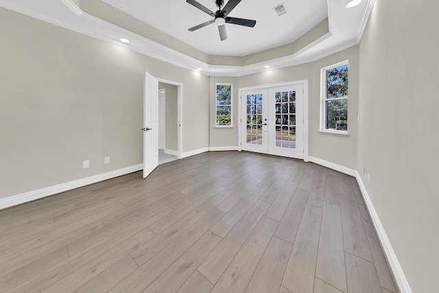 unfurnished room featuring french doors, hardwood / wood-style flooring, a wealth of natural light, and a tray ceiling