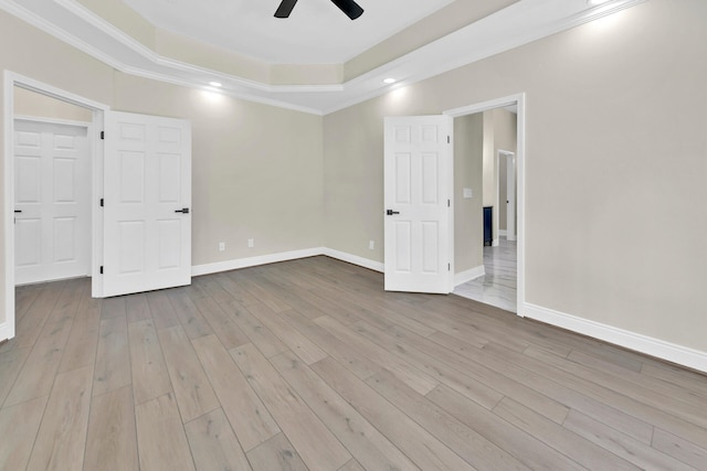 empty room with wood-type flooring, ceiling fan, and a tray ceiling