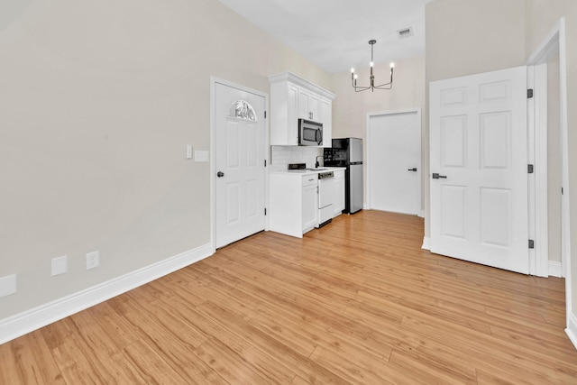 kitchen featuring white cabinets, tasteful backsplash, stainless steel appliances, and light wood-type flooring