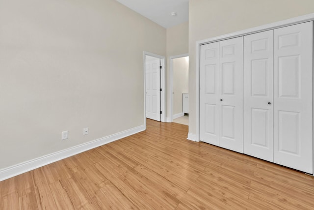 unfurnished bedroom with a closet, light hardwood / wood-style floors, and a high ceiling