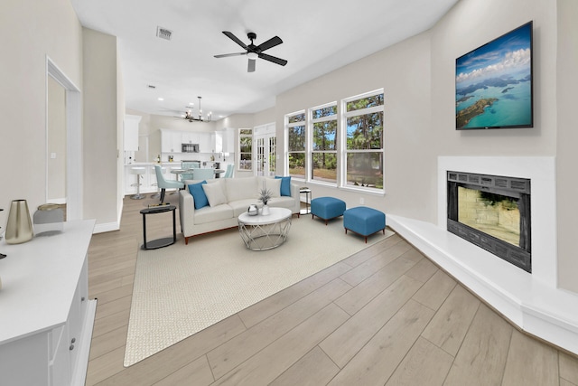 living room with light hardwood / wood-style flooring and ceiling fan with notable chandelier