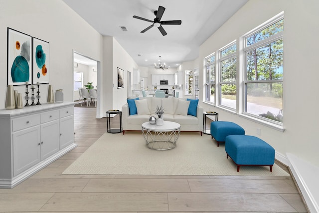 living room featuring ceiling fan with notable chandelier and light hardwood / wood-style floors