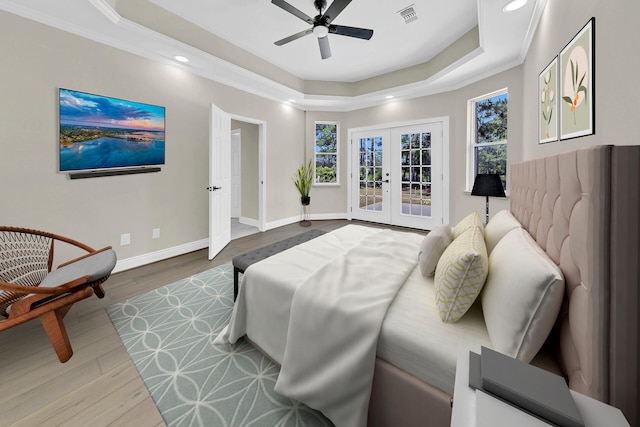 bedroom featuring wood-type flooring, french doors, crown molding, a tray ceiling, and ceiling fan