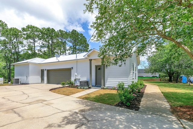 view of front of home featuring a garage, a front lawn, and central AC unit