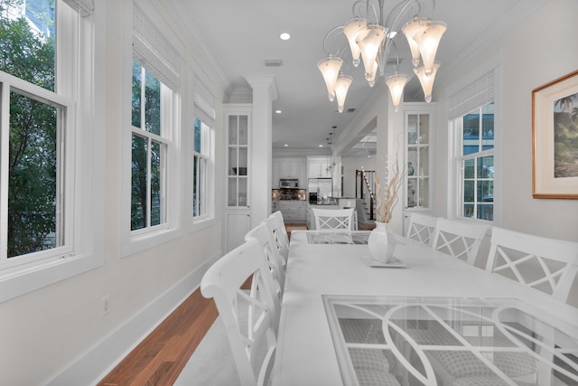 dining space featuring ornamental molding, a notable chandelier, and wood-type flooring