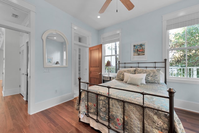 bedroom with dark hardwood / wood-style flooring, ceiling fan, and multiple windows