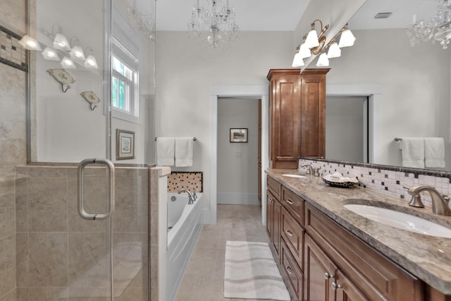 bathroom with tile flooring, vanity with extensive cabinet space, dual sinks, shower with separate bathtub, and an inviting chandelier