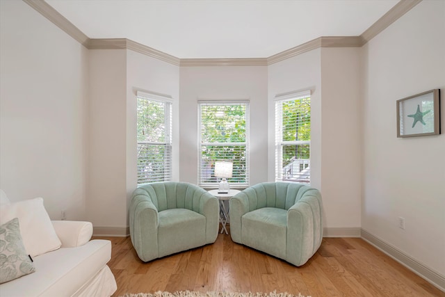 living area with wood-type flooring, plenty of natural light, and ornamental molding