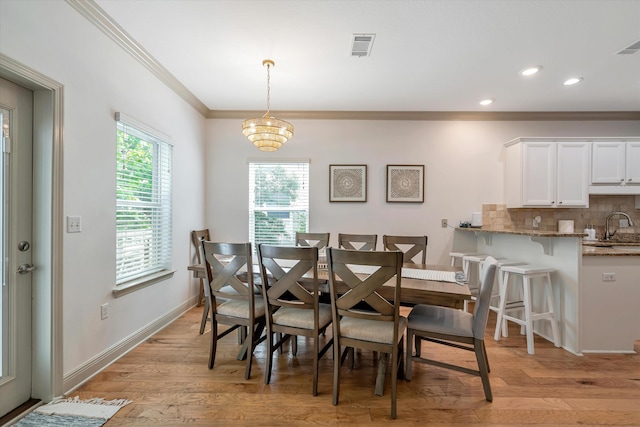 dining room featuring a chandelier, crown molding, light hardwood / wood-style flooring, and sink