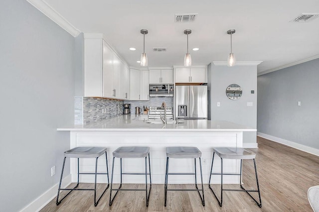 kitchen with white cabinetry, hanging light fixtures, stainless steel appliances, and sink