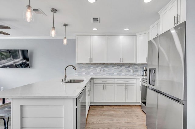 kitchen featuring white cabinets, pendant lighting, sink, and appliances with stainless steel finishes