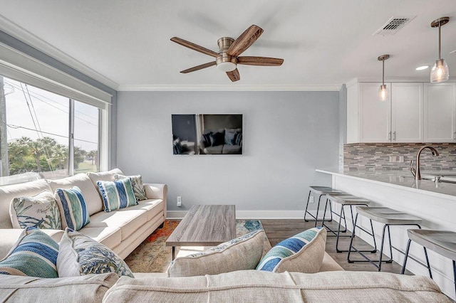 living room featuring ceiling fan, sink, dark hardwood / wood-style floors, and ornamental molding