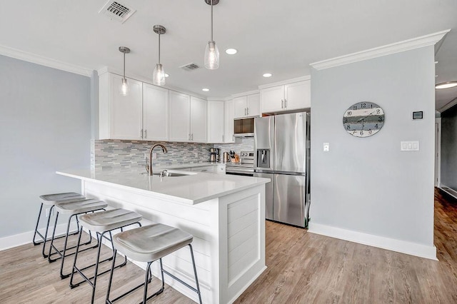 kitchen with a kitchen breakfast bar, hanging light fixtures, decorative backsplash, white cabinetry, and stainless steel appliances