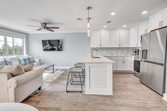 kitchen with pendant lighting, a breakfast bar, sink, white cabinetry, and stainless steel appliances