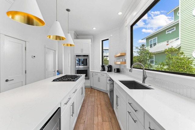 kitchen featuring appliances with stainless steel finishes, white cabinets, a sink, and light wood finished floors