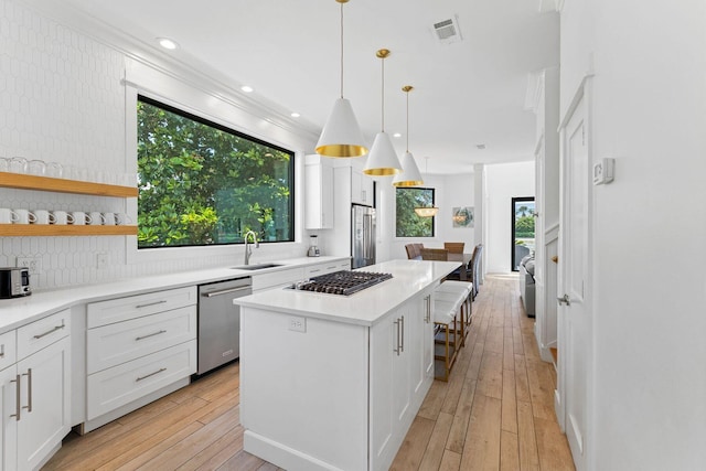 kitchen with stainless steel appliances, a center island, white cabinetry, and light wood finished floors