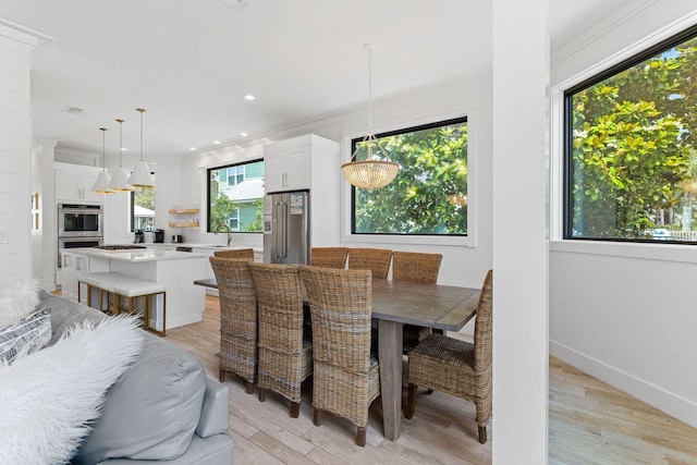 dining room with baseboards, light wood finished floors, ornamental molding, and recessed lighting