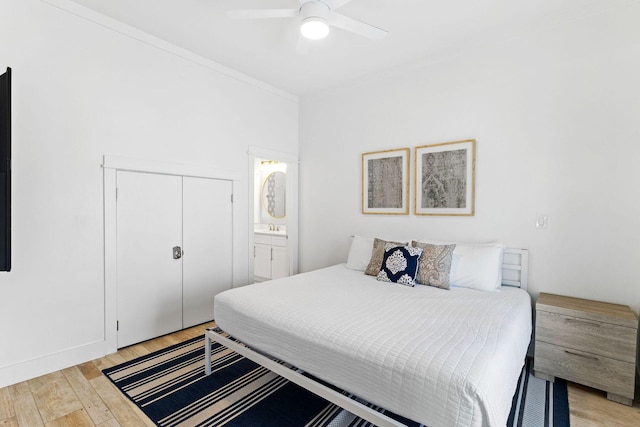 bedroom with a ceiling fan, connected bathroom, crown molding, light wood-style floors, and a closet