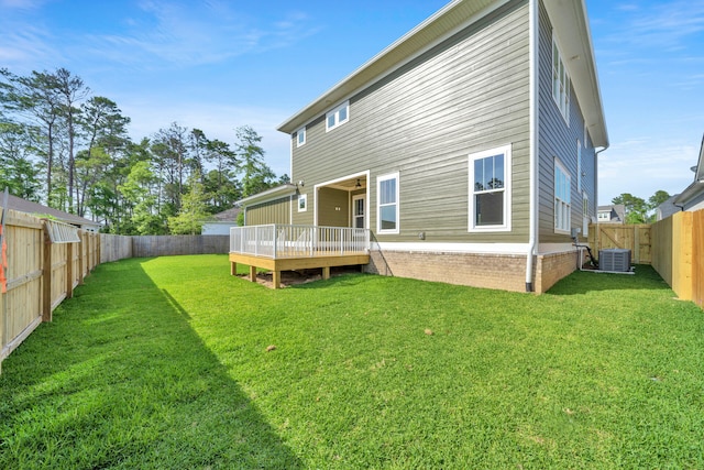 rear view of property featuring a lawn, cooling unit, and a wooden deck