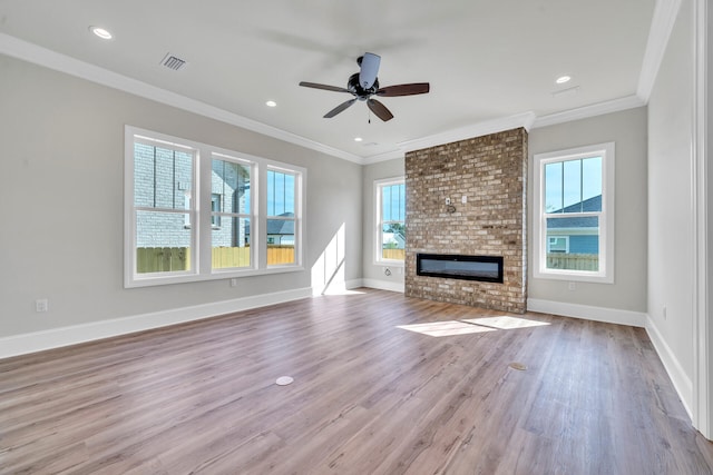 unfurnished living room with light wood-type flooring, a brick fireplace, ceiling fan, and ornamental molding