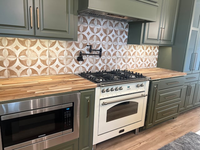 kitchen with stainless steel microwave, light hardwood / wood-style flooring, white range with gas stovetop, premium range hood, and decorative backsplash