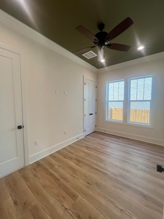 empty room with crown molding, ceiling fan, and light wood-type flooring