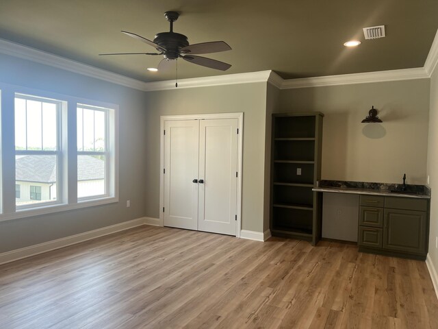 unfurnished bedroom with ceiling fan, sink, light hardwood / wood-style floors, a closet, and ornamental molding