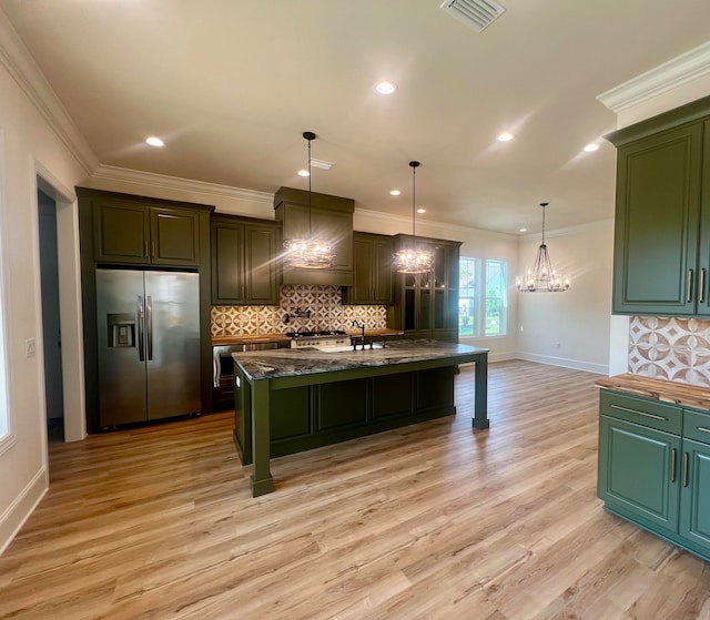 kitchen featuring a chandelier, appliances with stainless steel finishes, premium range hood, and an island with sink