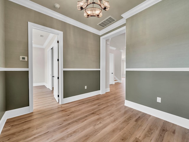 unfurnished dining area with crown molding, a notable chandelier, and light wood-type flooring