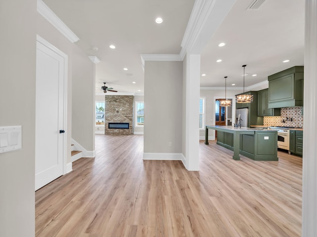 kitchen featuring ornamental molding, a center island with sink, light hardwood / wood-style flooring, and green cabinets