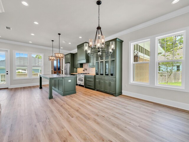 kitchen with a healthy amount of sunlight, a kitchen bar, appliances with stainless steel finishes, and green cabinetry