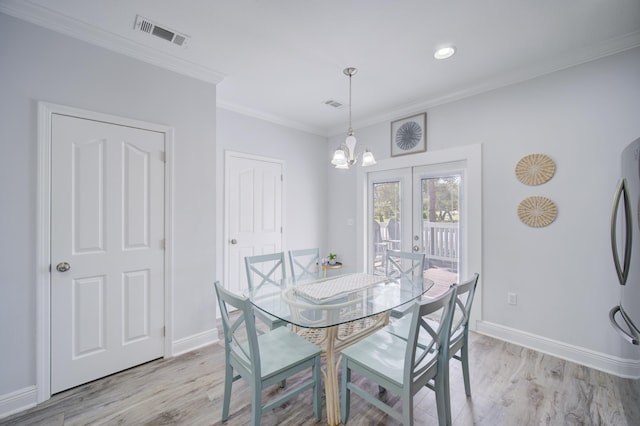 dining area featuring french doors, a notable chandelier, crown molding, and light wood-type flooring