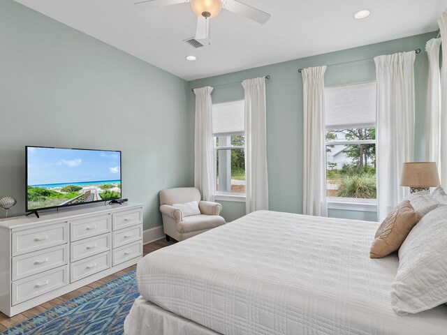 bedroom featuring wood-type flooring, ceiling fan, and multiple windows