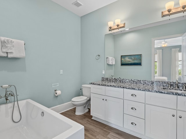 bathroom with vanity with extensive cabinet space, double sink, a bathing tub, hardwood / wood-style flooring, and toilet