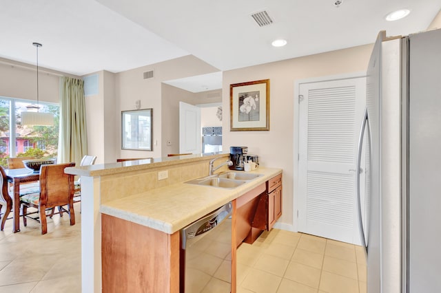 kitchen featuring decorative light fixtures, light tile flooring, white refrigerator, sink, and stainless steel dishwasher