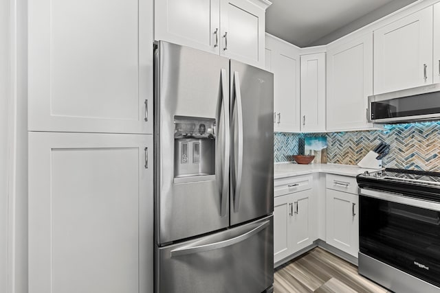 kitchen featuring appliances with stainless steel finishes, backsplash, light hardwood / wood-style floors, light stone counters, and white cabinets