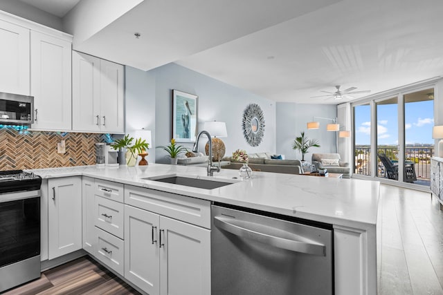 kitchen with kitchen peninsula, stainless steel appliances, sink, tasteful backsplash, and ceiling fan