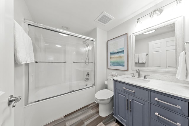 full bathroom with vanity with extensive cabinet space, toilet, and bath / shower combo with glass door