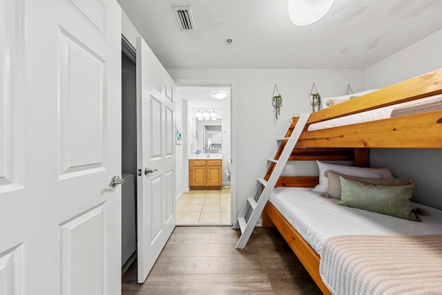 bedroom featuring ensuite bathroom and light wood-type flooring