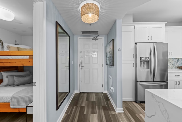 interior space with stainless steel fridge with ice dispenser, wood-type flooring, tasteful backsplash, light stone counters, and white cabinets