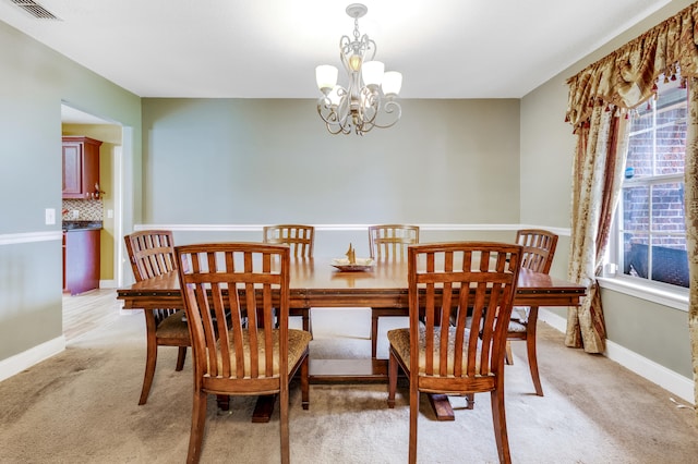 dining room featuring light colored carpet, a chandelier, a wealth of natural light, and visible vents