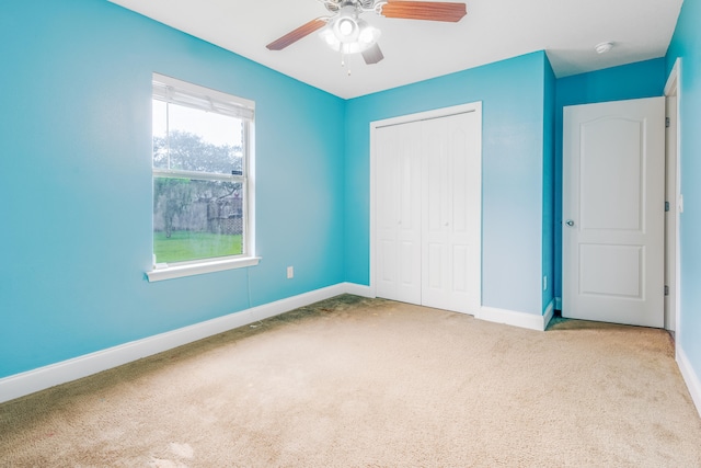 unfurnished bedroom featuring carpet floors, baseboards, ceiling fan, and a closet