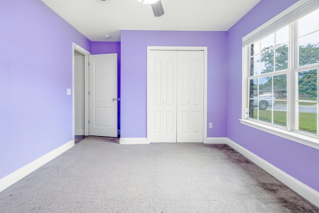 unfurnished bedroom with a closet, a ceiling fan, carpet, and baseboards