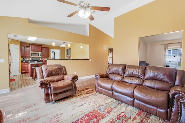 living room with light wood-style floors, baseboards, ceiling fan, and high vaulted ceiling