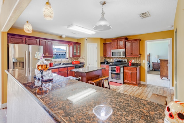 kitchen with visible vents, backsplash, a center island, and stainless steel appliances