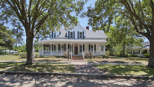 farmhouse-style home featuring a porch and a front yard