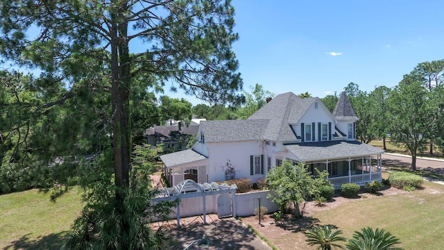 back of property featuring a sunroom and a lawn