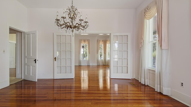 unfurnished dining area featuring wood-type flooring and a chandelier