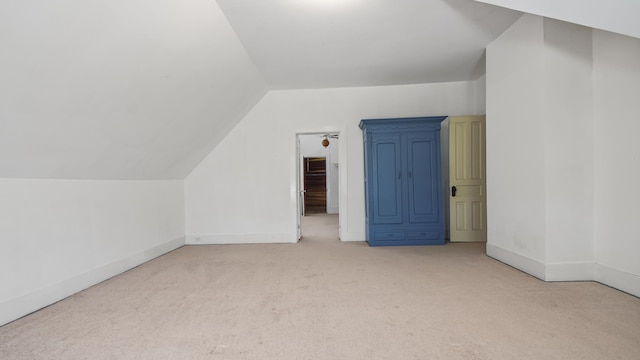 additional living space featuring light colored carpet and vaulted ceiling